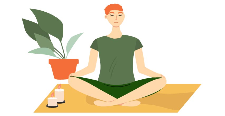 person sitting cross legged and meditating next to candles and a plant